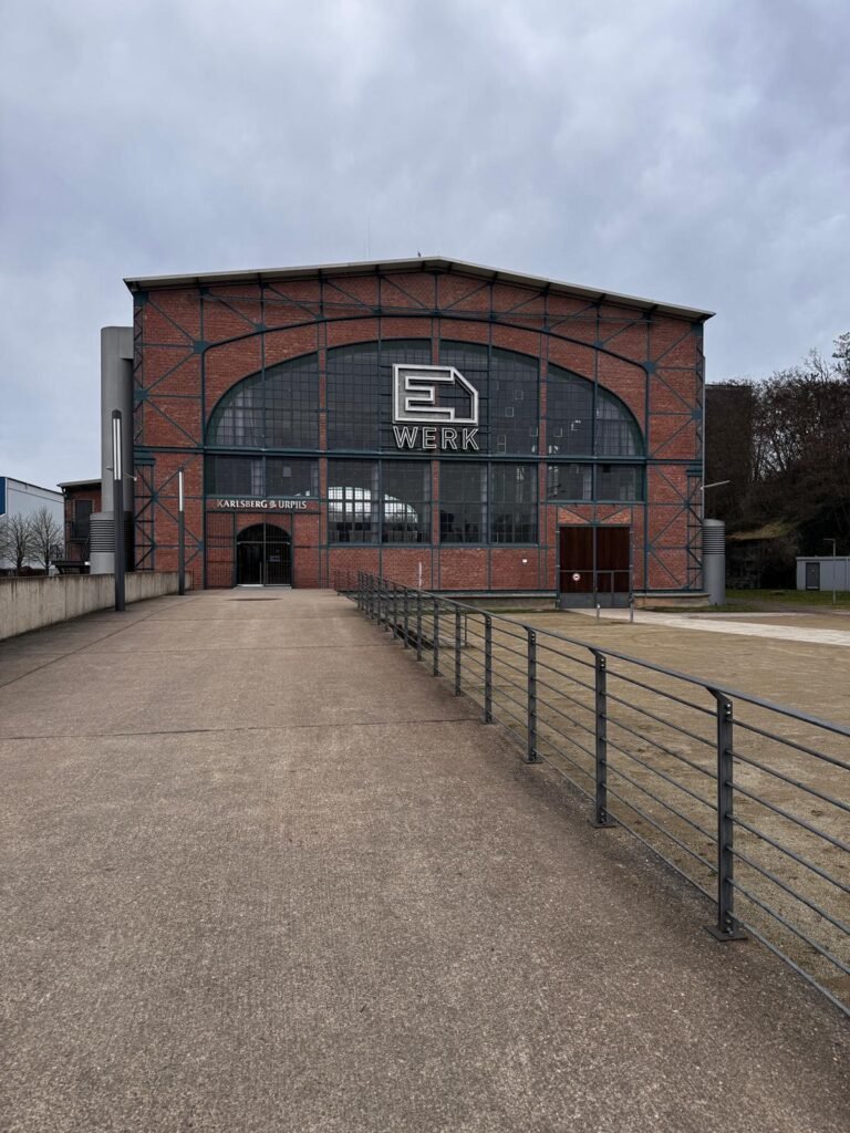 Backsteingebäude des E WERK Saarbrücken mit beleuchtetem E-WERK-Schriftzug über dem Eingang