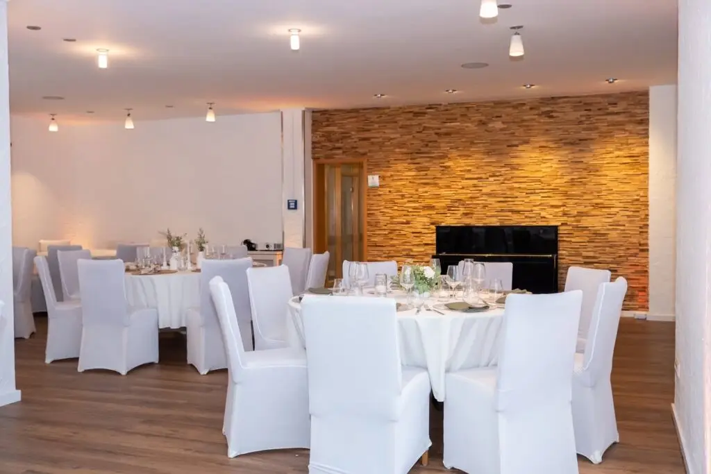 Festlich gedeckte Tische vor der Holzwand im Saal