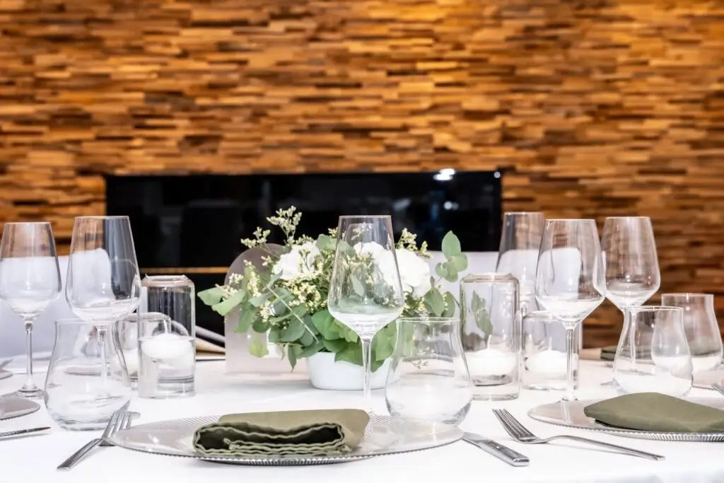 Gedeckter Tisch mit Blumen vor der Holzwand
